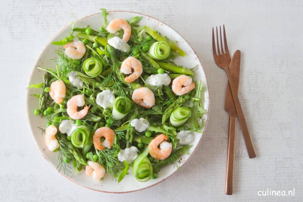 Groene voorjaarssalade van rucola, groene asperges, garnalen en dille