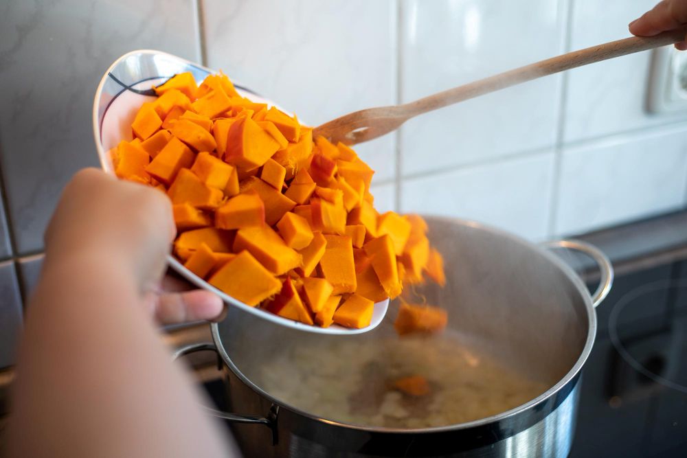 een persoon die zoete aardappelen in een pan gooit om te koken